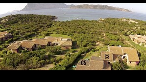 Luftaufnahme eines Küstenresorts mit Villen, Meerblick und einem Bergpanorama.