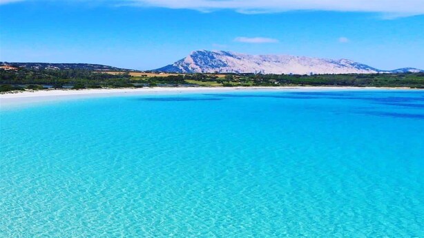 Ein klares, blaues Meer mit einem Berg im Hintergrund.