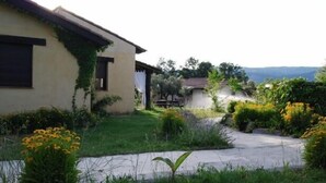 Una casa con jardín, camino de entrada pavimentado y vistas a las colinas.
