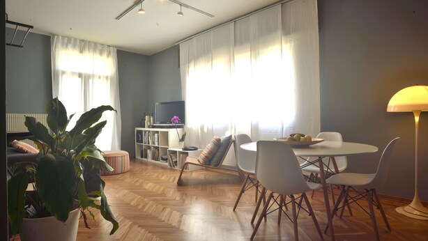 A modern living room with a wooden herringbone floor, a dining area with white chairs, a round table, and a potted plant. - Flat design in Treviso. Easy connection to Venice (Treviso)