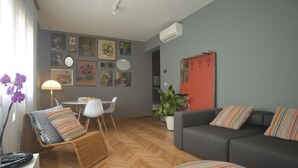 A living room with a sofa, a chair, a dining table, and a potted plant. - Flat design in Treviso. Easy connection to Venice (Treviso)