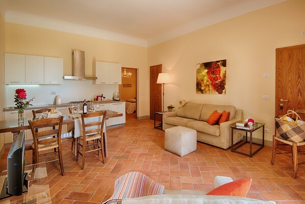 Un salon comprenant un canapé, un pouf et un coin repas avec des chaises et une table.