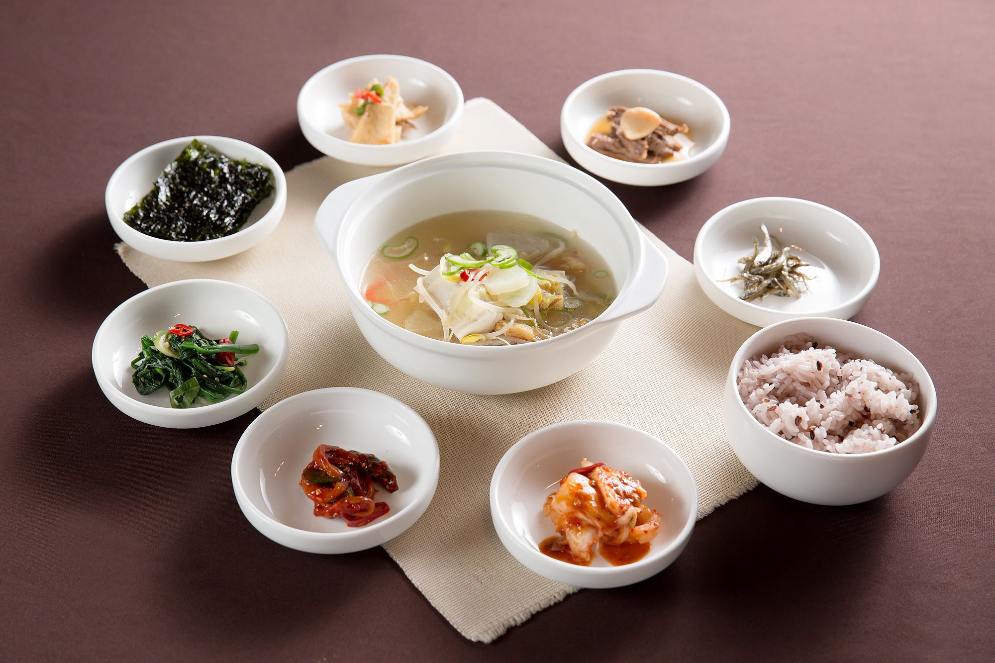 A table with various dishes including a bowl of soup, side dishes, and condiments.