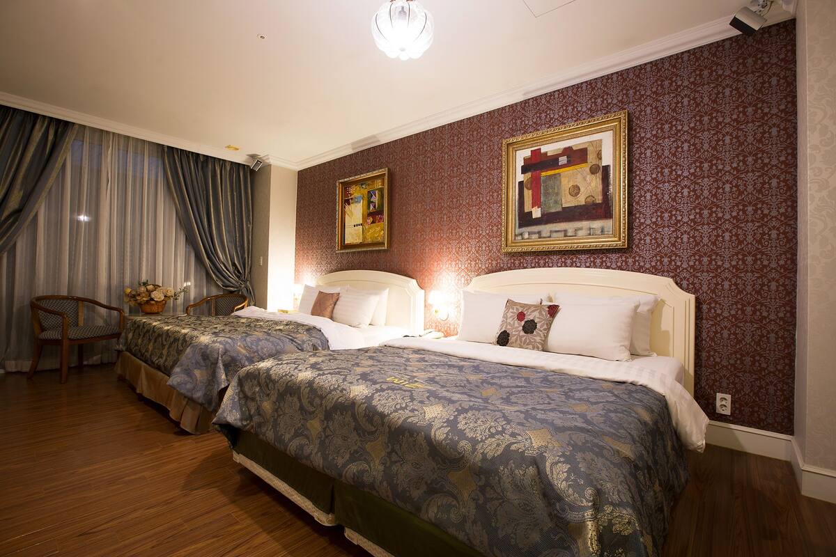 A hotel room with two beds, a chair, and a nightstand.