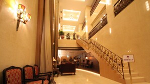 Un vestíbulo de hotel con una escalera, zona de estar y un cartel que indica la dirección al ascensor.