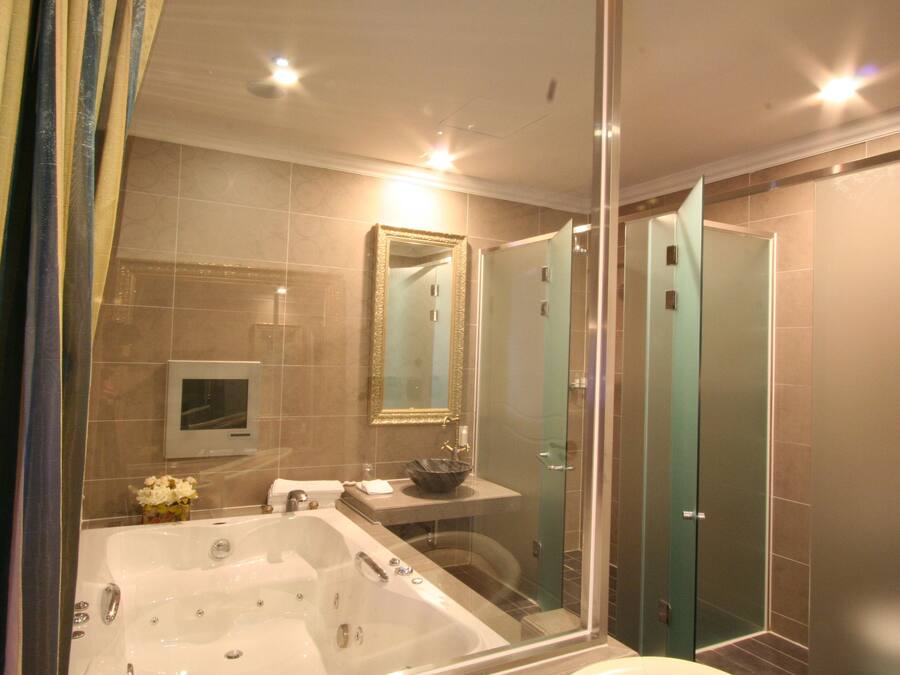 Un baño moderno con una bañera grande, ducha con mampara de vidrio y tocador con lavamanos y espejo.