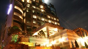 Un hotel de varios pisos con una sección circular y un área de entrada techada.