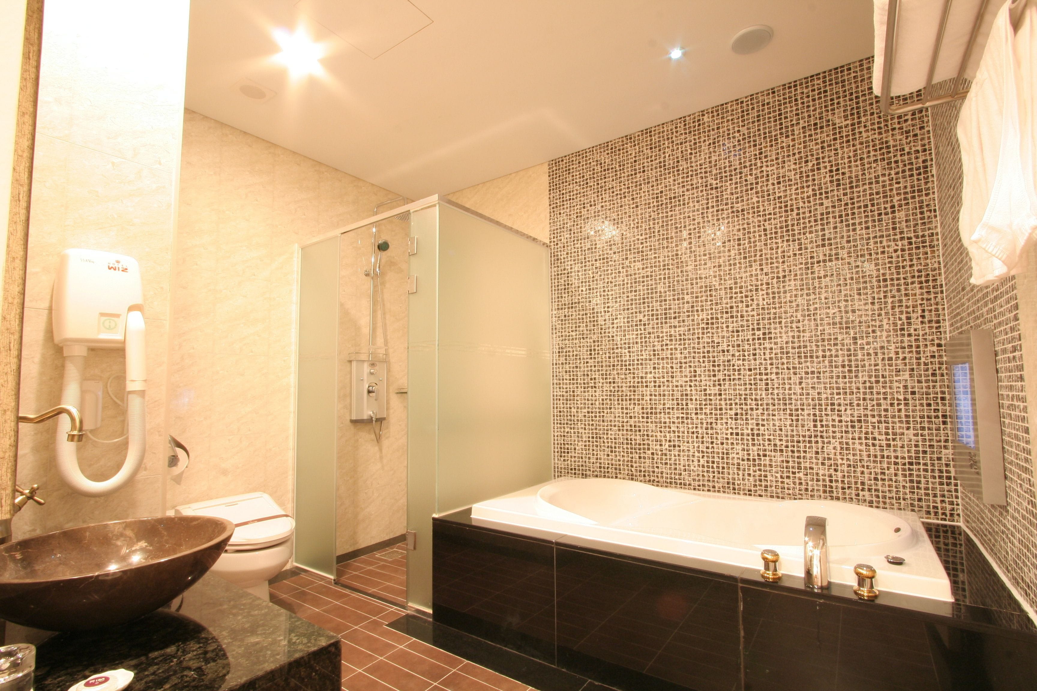 A modern bathroom with a glass-enclosed shower, a large freestanding bathtub, and a vessel sink.