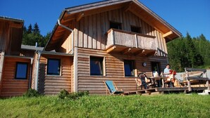 Une cabane en bois dotée d’un balcon, d’un espace extérieur aménagé et offrant une vue dégagée sur la forêt environnante.