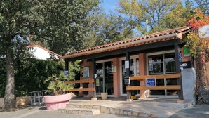 A building with a tiled roof, a reception desk, and a sign indicating a reception area. - SAINT-TROPEZ Bungalow in vacation park with pool - CÔTE D'AZUR  (Gassin)