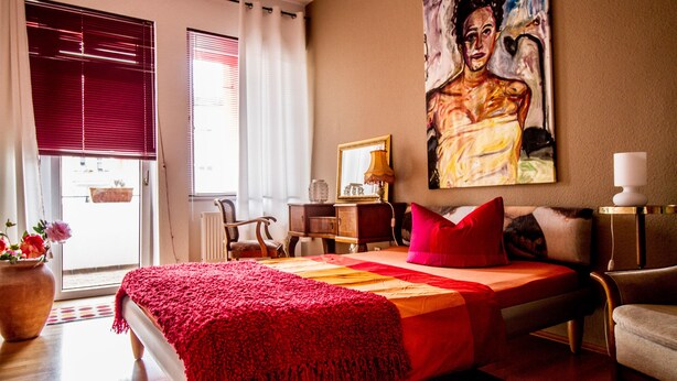 Een slaapkamer met een bed, schilderij, lamp en stoel.