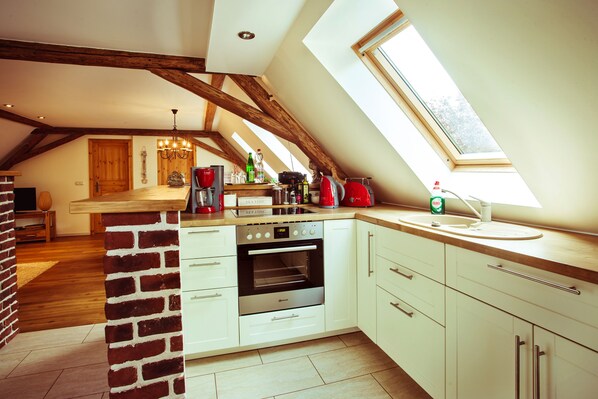A kitchen with a brick wall, white cabinets, a built-in oven, and a skylight.
