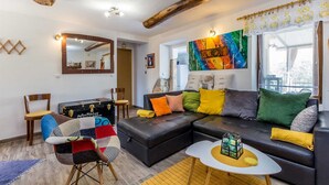 Een moderne woonkamer met een hoekbank, een houten salontafel en een kleurrijk abstract schilderij.