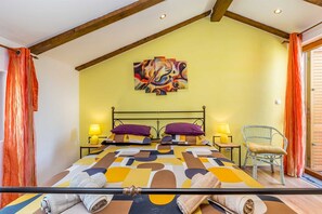 A room with a bed, two bedside tables with lamps, a chair, and a colorful abstract painting on the wall.