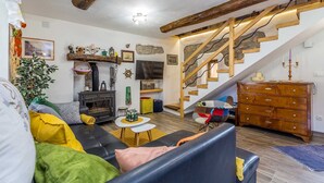Een gezellige woonkamer met een open haard, een trap en een houten dressoir.