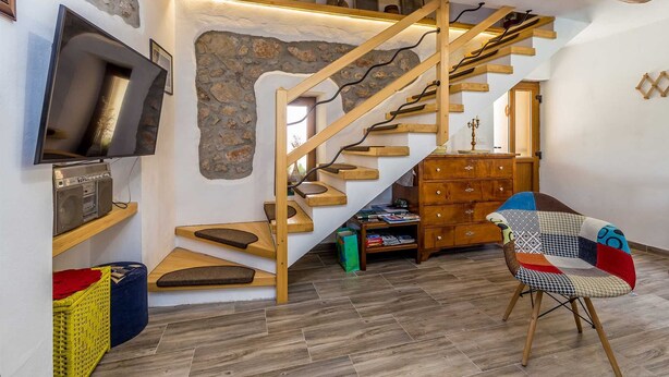 Een modern interieur met een houten trap, een flatscreen televisie, een vintage radio en een gezellige zithoek.