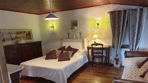 Une chambre confortable avec un lit en bois, un bureau avec une chaise et une petite table avec une lampe.