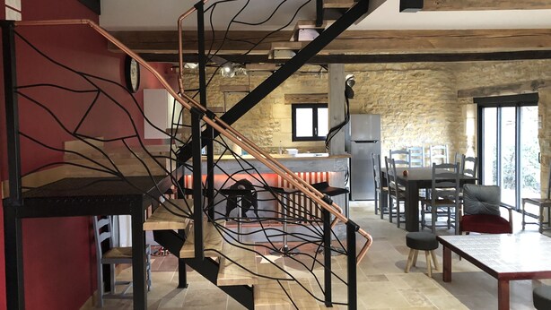 A modern kitchen with a stone wall, a wooden dining table, and a staircase with exposed beams. - Traditional sluice-gate truss hones some on 10 hectares of ground-swimming pool (Gourdon)