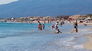 Une plage bondée où les gens se baignent et prennent des bains de soleil.