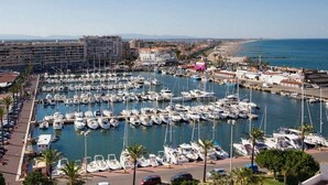 Un port de plaisance où de nombreux bateaux sont amarrés, entouré de bâtiments et offrant une vue dégagée sur la mer.