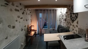 Een keuken met een stenen muur, houten plafond, een eettafel en een spoelbak.