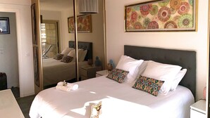 Habitación de hotel con una cama grande, un armario, una mesita de noche y un espejo.