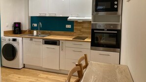 Een compacte keuken met witte kastjes, een ingebouwde magnetron en een oven.