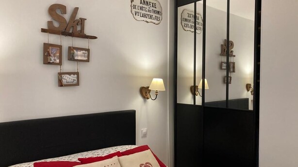 Een slaapkamer met een bed, een bord aan de muur en een spiegel.