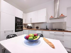A modern kitchen with white cabinets, a black oven, a stainless steel range hood, and a bowl of fruit on the counter. - Gaîté Paris, 5 Br / 3 Ba, 10 ppl, 170 m² (Paris)