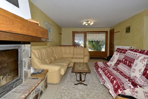 Een woonkamer met een bank, een bijzettafeltje, een open haard en een gestreept plaid.
