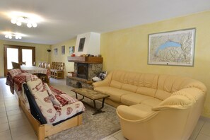 A living room with a sofa, a coffee table, a fireplace, and a dining area with chairs and a table.
