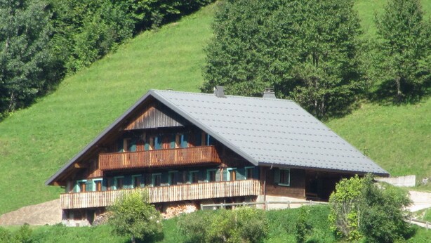 Un chalet en bois doté d’un toit à pente, de plusieurs balcons et de fondations en pierre.