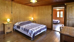 Ein Schlafzimmer mit Holzwänden, einem Bett, zwei Nachttischlampen und einer Tür zu einem anderen Raum.