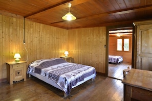 Une chambre à coucher aux murs lambrissés, avec un lit, deux lampes de chevet et une porte donnant sur une autre pièce.