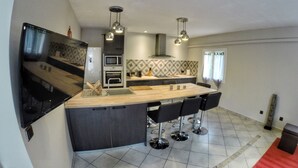 A modern kitchen with a central island, built-in appliances, and pendant lighting. - Charming house surrounded by vineyards  (Rochefort-du-Gard)