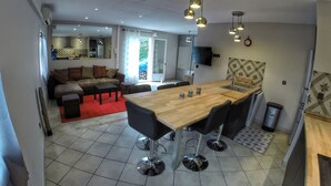 A modern kitchen with a wooden island, bar stools, and a dining table. - Charming house surrounded by vineyards  (Rochefort-du-Gard)