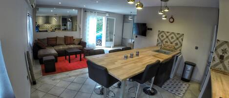 Una cocina moderna con una isla de madera, taburetes de bar y una mesa de comedor.