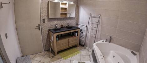 A bathroom with a bathtub, a sink, a vanity, and a towel rack.