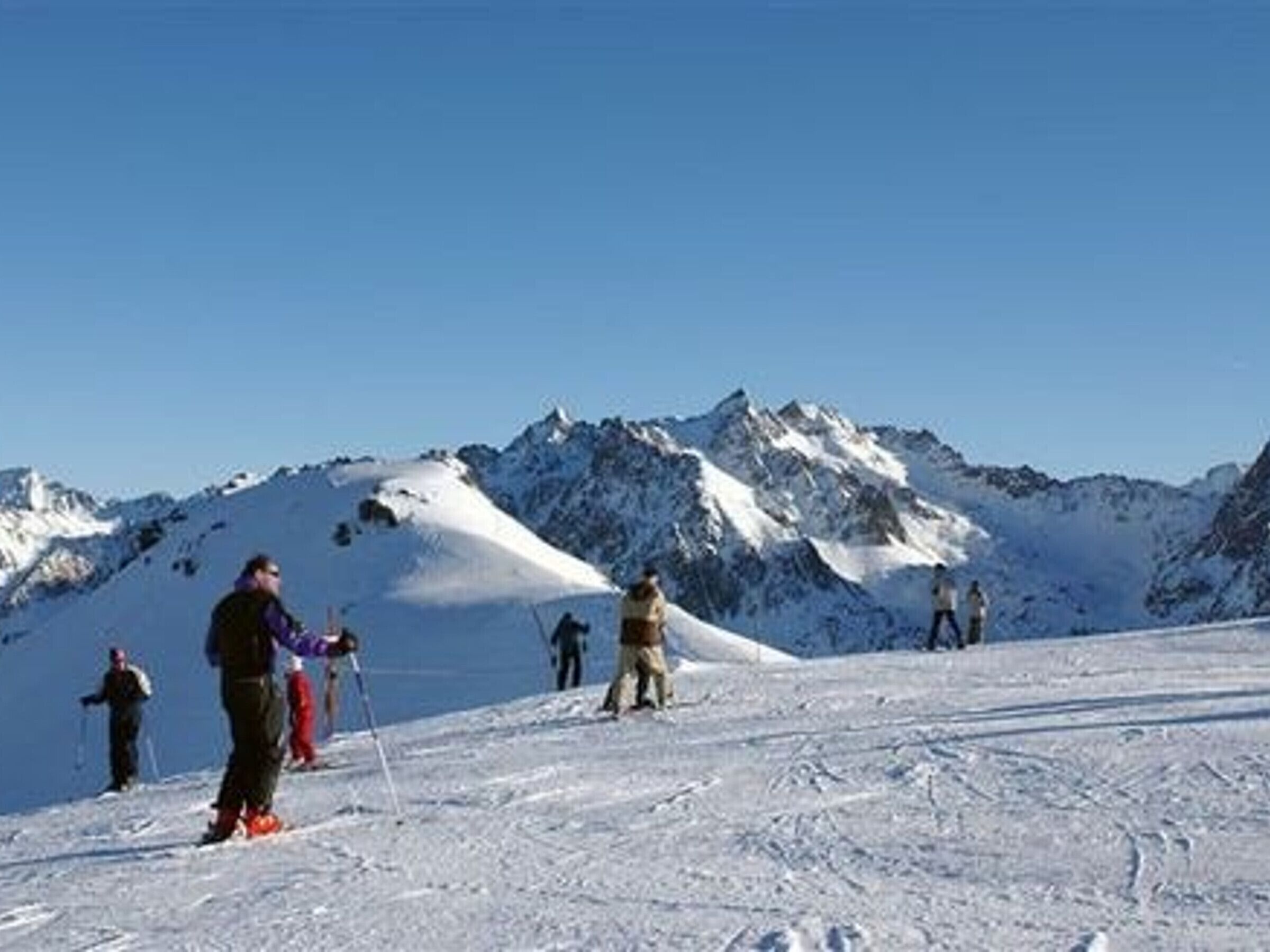 Pendiente nevada de una montaña con esquiadores y snowboarders.
