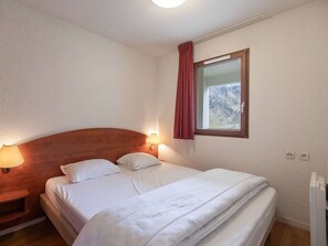 Cama bem arrumada com lençóis brancos, cabeceira de madeira e duas luminárias de apoio.