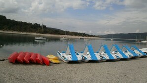A row of small boats on a pebbled beach with calm water and boats in the background. - Domaine de La Tourelle, grand studio (Lorgues)