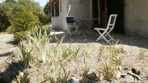 An outdoor seating area with a table and two chairs, surrounded by a gravel patio and sparse vegetation. - Domaine de La Tourelle, grand studio (Lorgues)