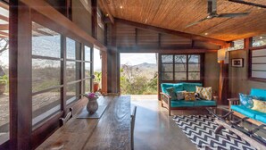 A spacious living area with a wooden ceiling, large windows, and a view of the outdoors.