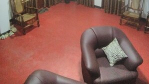 A room with a red carpet, two armchairs, a sofa, and curtains with a striped pattern.