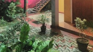 A courtyard with a staircase, potted plants, and a building with a balcony.