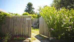 A wooden gate labeled "135 South" leading to a backyard with a wooden deck, a chair, and a flower bed. - Martha's Vineyard 1BR, Pets Ok, 10 Min walk to beach or Edgartowns shops! (Edgartown)