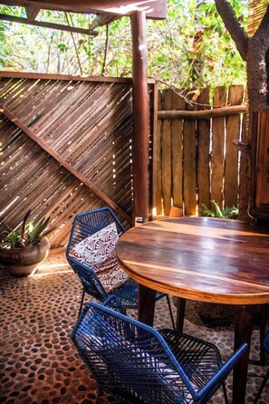 A wooden table with two blue chairs, surrounded by a wooden fence and a potted plant. - La Siesta Troncones  Surf Villa 1 (Troncones)