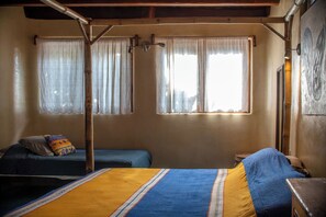 A room with a bed, two smaller beds, and a window with curtains. - La Siesta Troncones  Surf Villa 1 (Troncones)