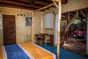 Una habitación con una cama, una mesita, una silla, una ventana y una puerta.