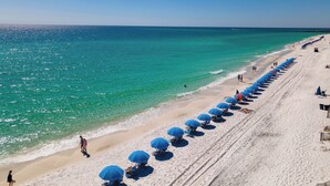 Une plage bordée d’une rangée de parasols bleus et de chaises de plage le long du rivage.